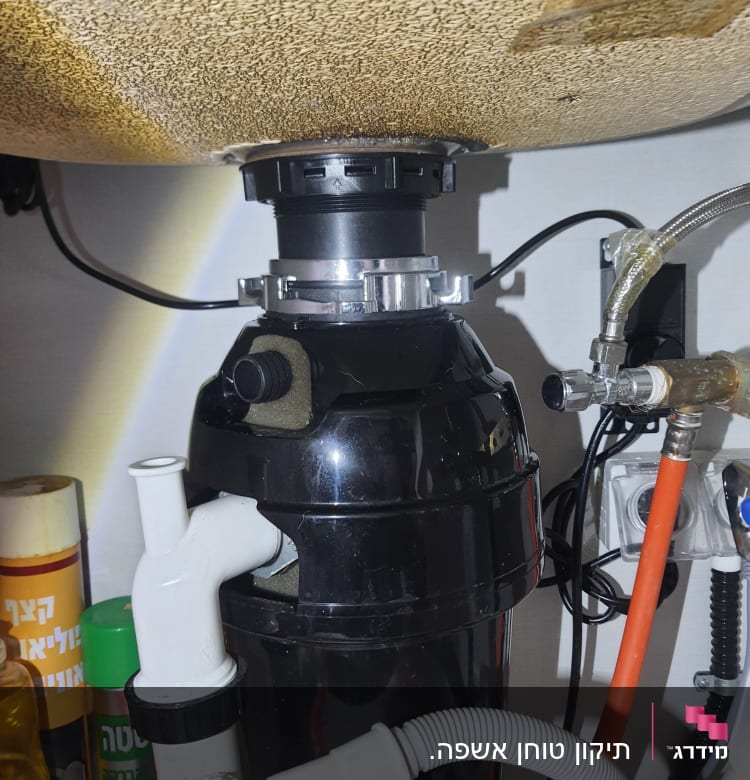 מתקן טוחן אשפה מתחת לכיור עם צינורות חיבור